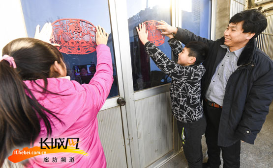 文安县剪纸艺人孟建华与孩子们一同贴窗花。王猛 摄