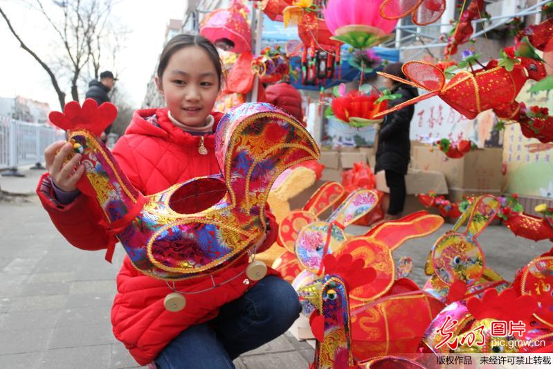 2017年2月6日,在扬州市街头一名小朋友正在挑选花灯鸡造型花灯.