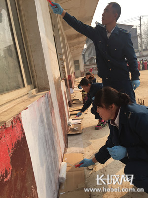 公交志愿者用心的粉刷墙壁。
