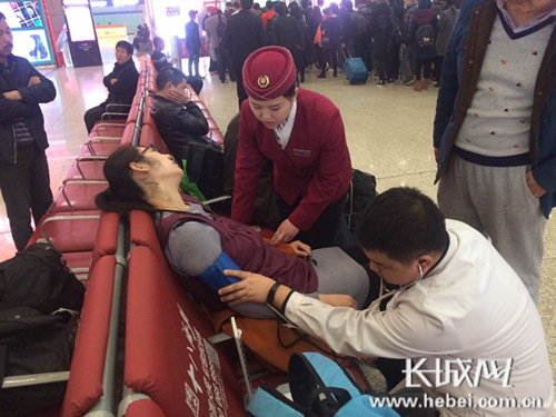 聂文亚协助驻站医生对晕倒旅客检查。