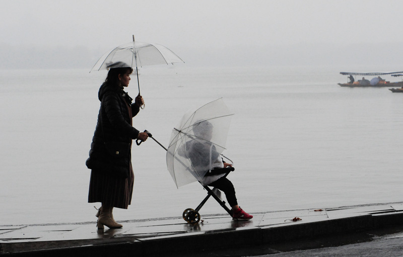 杭州迎来小雨天气 游客撑伞雨中游西湖
