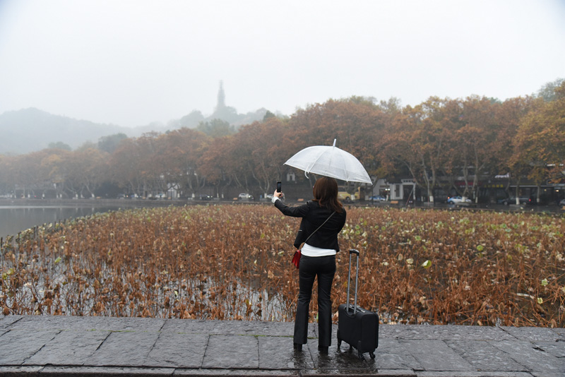 杭州迎来小雨天气游客撑伞雨中游西湖