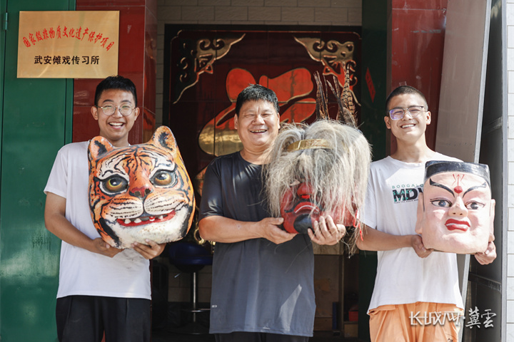 马增祥和自己的学生在武安傩戏传习所前展示傩戏人物面具