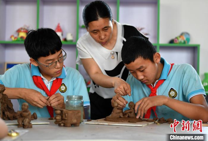 图为深泽县田家庄村小学，老师(中)指导学生制作泥塑。　翟羽佳 摄